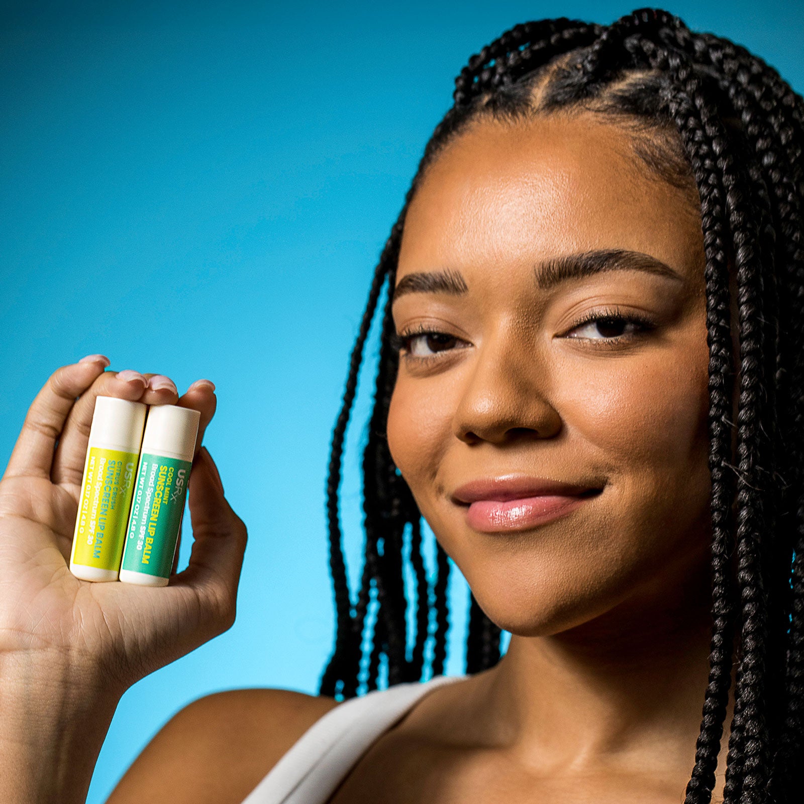 Woman holding 2 USRX Sunscreen Lip Balms in her hand