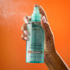 Woman spraying USRX Glow Boost AHA Body Mist in Nectarine Bellini