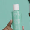 African American model using a textured white cotton pad to apply the Witch Hazel Brightening & pH Balancing Toner for a refreshed and renewed look
