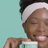 African American model holding the Even Tone Cleansing Bar 2oz which works to improve the appearance of dark marks
