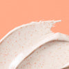 Thick off white swatch of Pumpkin Pore Detox Mask & Scrub containing small orange jojoba beads 