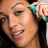 Woman dispensing Urban Skin RX YouthHero AM/PM Serum onto her face